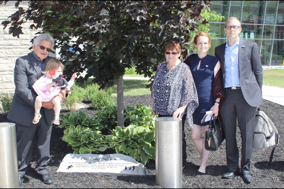 Posing with the plaque and tree unveiled Tuesday at OPP General Headquarters in Orillia in memory of Christopher Stephenson are, from left, Jim Stephenson (Christopher's dad), holding his granddaughter, Lily, Anna Stephenson (Christopher's mom), Amanda Stephenson-McGregor (Christopher's sister) and Cameron McGregor (Amanda's husband). Nathan Taylor/OrilliaMatters