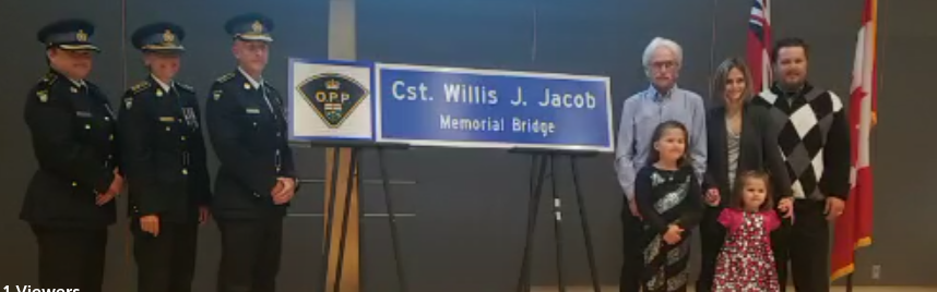 Family members and OPP officials unveil a replica of the sign that has been placed on the bridge at the intersection of Highways 11 and 12 in memory of Const. Willis J. Jacob, who was killed in the line of duty near that spot in 1958. OPP Photo