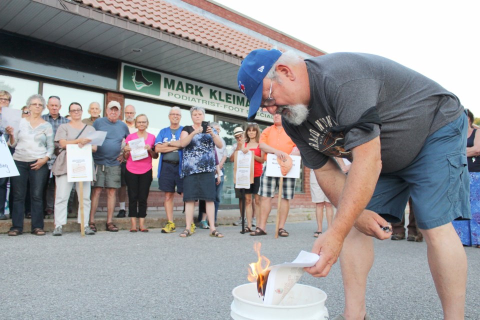 Dennis Rizzo sets fire to a copy of the Canadian Charter of Rights and Freedoms on Monday night. Dozens showed up at Simcoe North MPP Jill Dunlop's Orillia office to protest her government's use of the notwithstanding clause. Nathan Taylor/OrilliaMatters