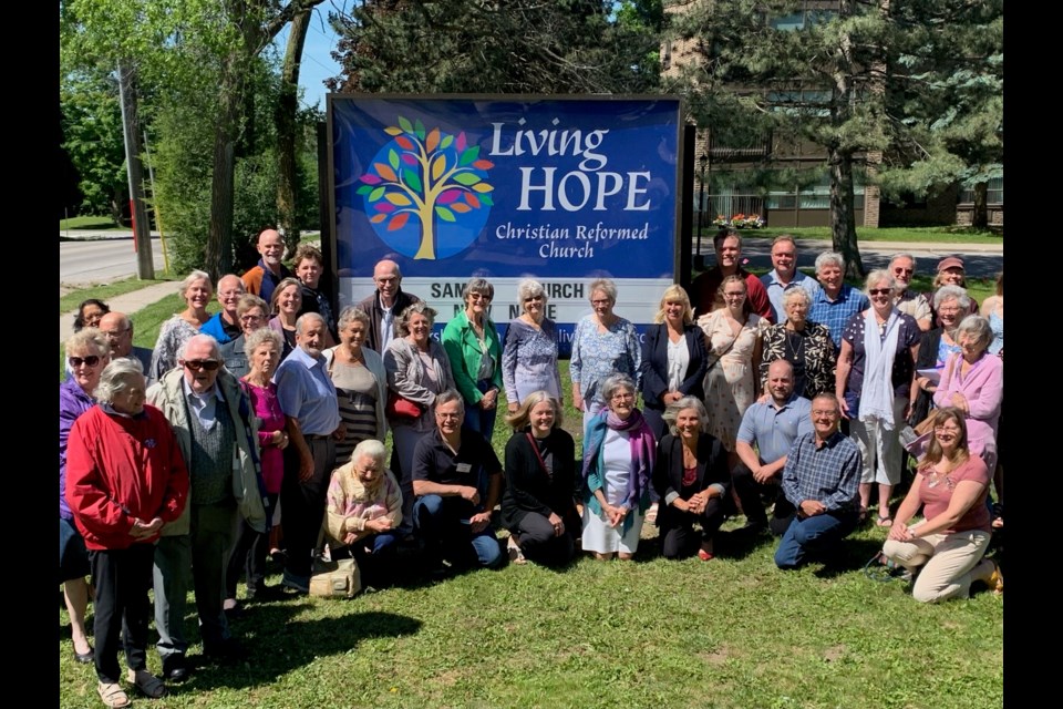 People gather by the new sign at Living Hope Christian Reformed Church on Fittons Road West.