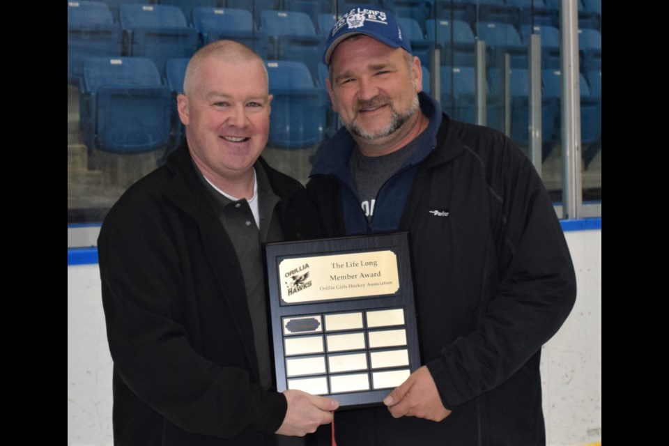 Orillia Girls Hockey Association vice-president Darrin Dunn presents Glenn Whitten, right, with the organization’s Life Long Member Award Friday night at Rotary Place. Supplied photo