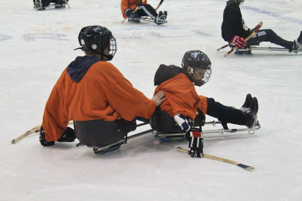 A member of the Georgian Sliders helps an Orillia Youth Centre player get upright after the youngster tipped his sled Thursday during the fifth annual Sunshine Sledge Hockey Tournament at Rotary Place. Nathan Taylor/OrilliaMatters