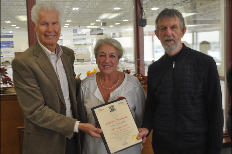Orillia Curling Club members Joe Fecht, left, and Gail Brown were on hand as Coun. Tim Lauer presented a certificate from the city recognizing the club’s 20 years at Barnfield Point. Andrew Philips/OrilliaMatters