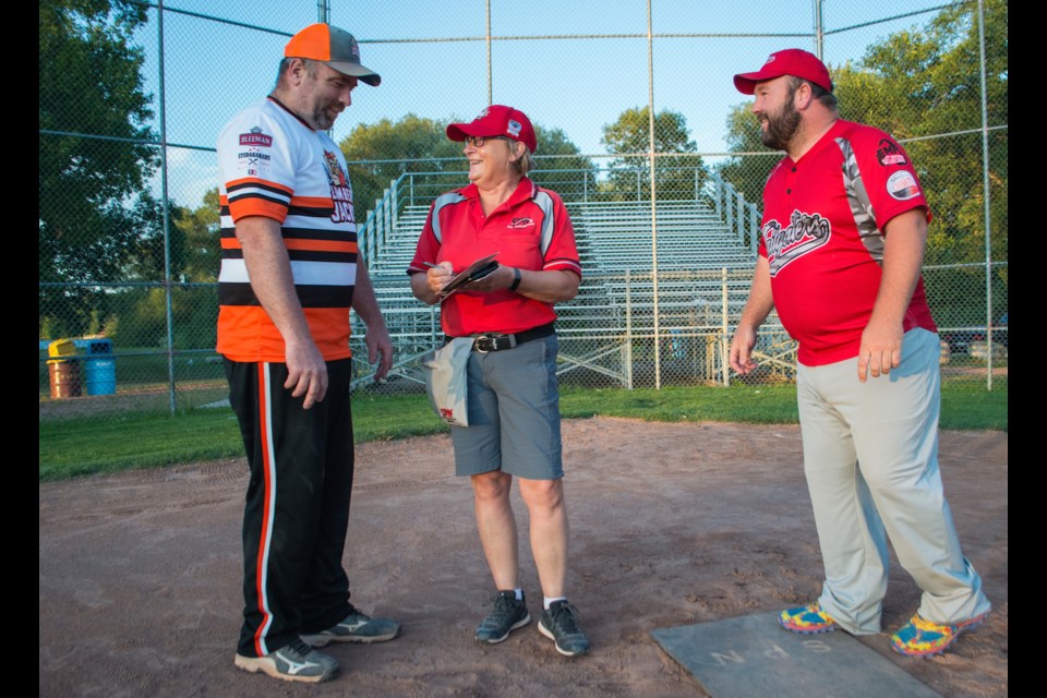 Pam Mogridge, the umpire-in-chief for Orillia Slo-Pitch, exchanges lineup cards with coaches from two local teams during a recent game. Tyler Evans/OrilliaMatters