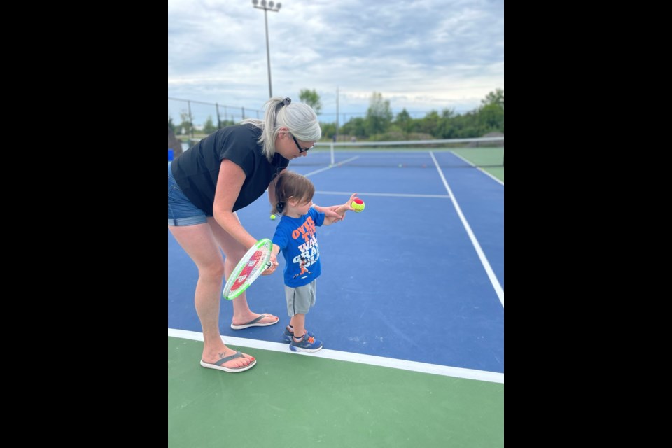 Kate Mulligan attempts to teach two-year-old Bo the finer points of tennis. 