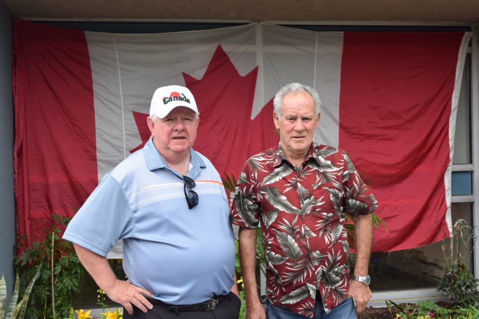 Henry McCambridge, left, with Al Madore. The large flag behind them once served atop the Peace Tower flagpole, McCambridge says.
