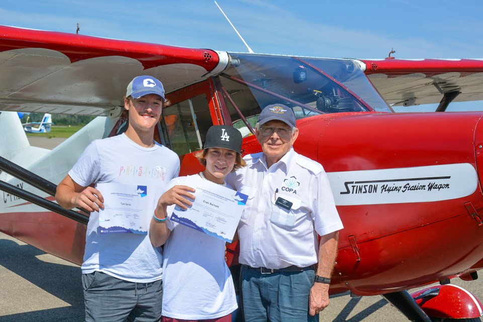 COPA pilot Adrian Verburg with his Stinson monoplane, and Tyler and Evan Barnett who he took for a flight.