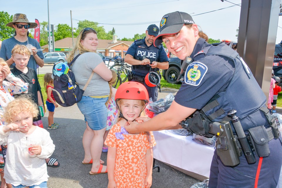 NRPS officer Jerri Eymann straps a helmet onto the head of Kyla, whose mom drove her all the way from Fort Erie.
