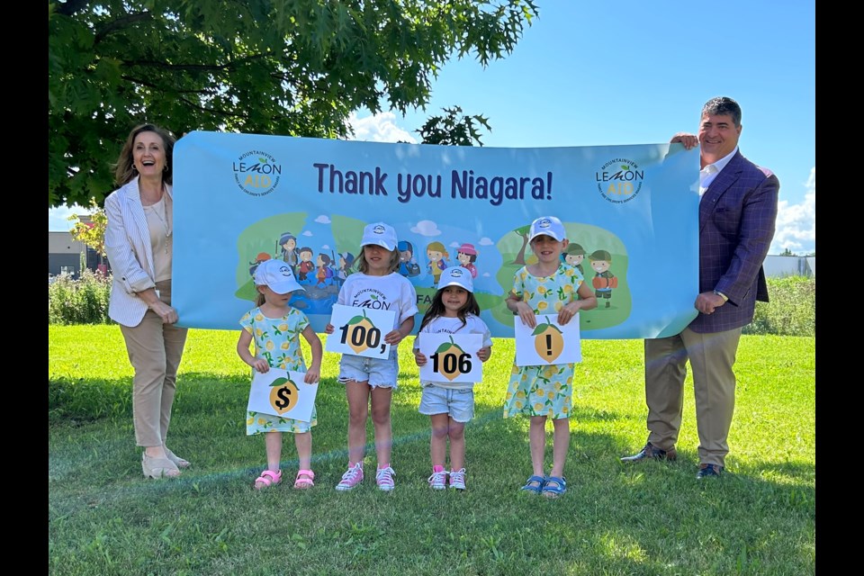 Young LemonAIDers help FACS Niagara CEO Anna Bozza (left) and Mountainview Building Group president Mark Basciano reveal the results of this year’s Mountainview LemonAID Day for FACS Niagara