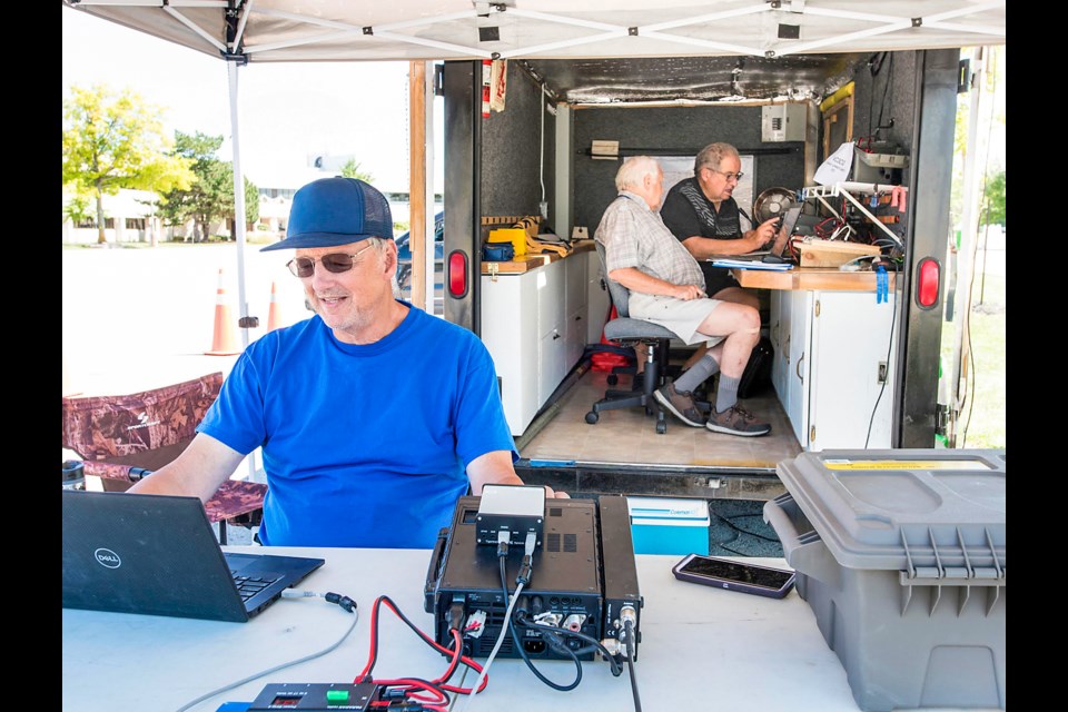 Kevin Lemon (VE3RRH), Glenn Holden (VE3NDW) and Henry Jarzyna (VA3OV) in a trailer set up in a parking lot next door to the Canada Summer Games site last summer, and the Summer Games' unique call sign.