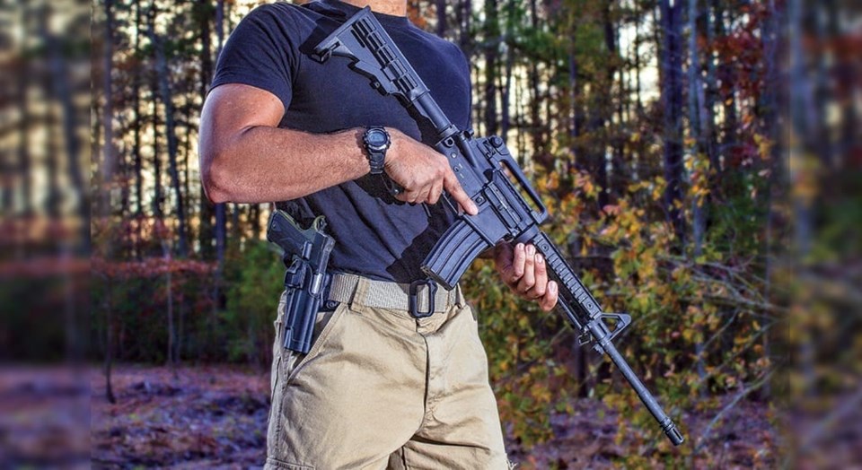 Man with a sidearm and Ar-15 that is on guard in the woods
