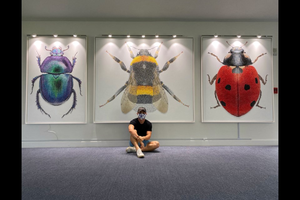 Jonah Waterous in front of a selection of his art.