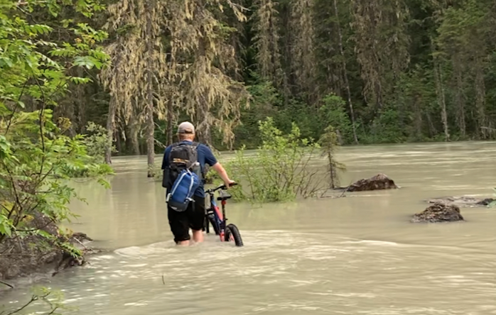 Geoff Barrie pushes his bike through high water along the Berg Lake Trail earlier this summer. 