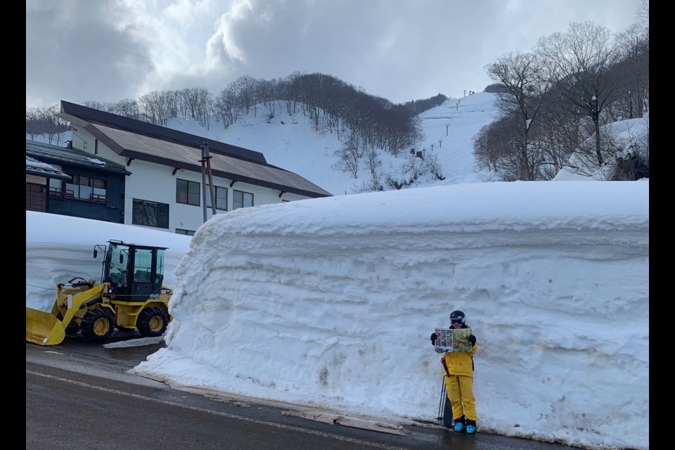 PIQUE’N JAPPOW Mandy Rousseau poses by gigantic snowbanks in Seki Onsen, Japan, with a copy of Pique Newsmagazine. In the background is the pizza box chairlift.