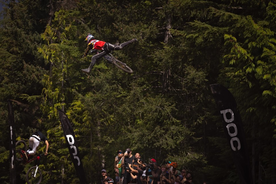 A group of fans looks on as two riders launch themselves at the 2023 Crankworx Whistler Whip-off.