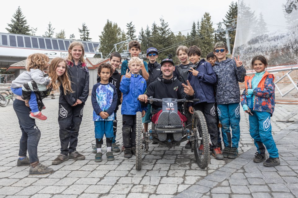 Various Kidsworx racers smile for the camera alongside one of 2023's adaptive athletes.