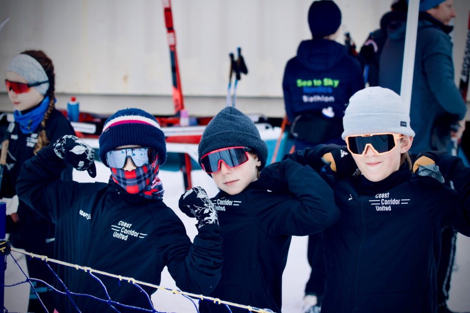 Three young skiers flex for the camera, dressed in their Coast Corridor United jackets.