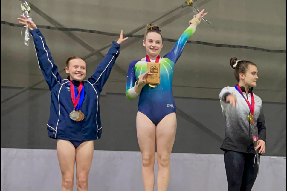 Whislter gymnasts Kirra Douglas (middle) and Sienna Osborn (left) stand on the podium at the 2023 Garden City Invitational.