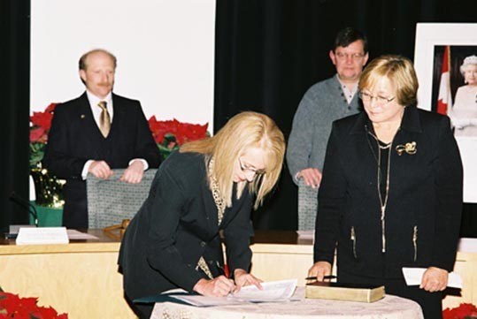 Nancy Wilhelm-Morden signs on for another term as councilor in front of Madam Justice Sunni S. Stromberg-Stein, watched by Mayor Ken Melamed and Councilor Gordon McKeever. Photo by Maureen Provencal