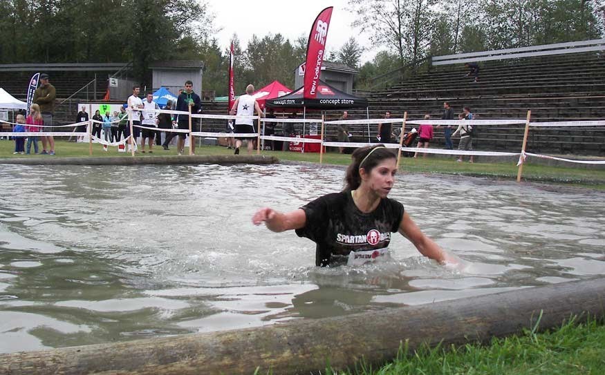 SOGGY SPARTAN Jessica Coulter prepares to emerge from from the logger's sports birling pond to cross the Super Spartan Race finish line. Photo by John French