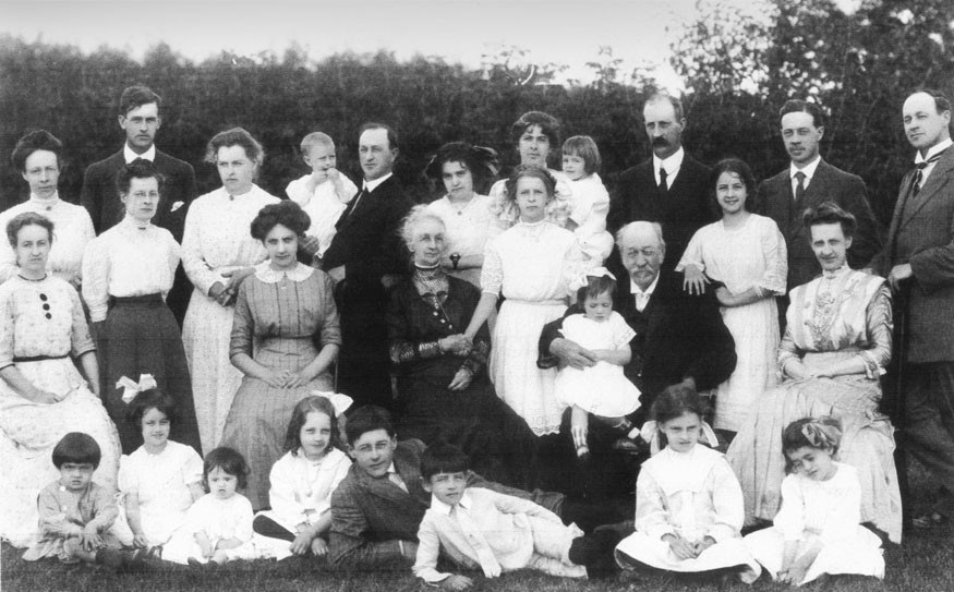 Douglas family picture 1911. In this Douglas family picture, John Barker's mother is the one-year-old seated on the ground on the left next to her sister, Margaret, with the bow in her hair — third from the left on the bottom row;