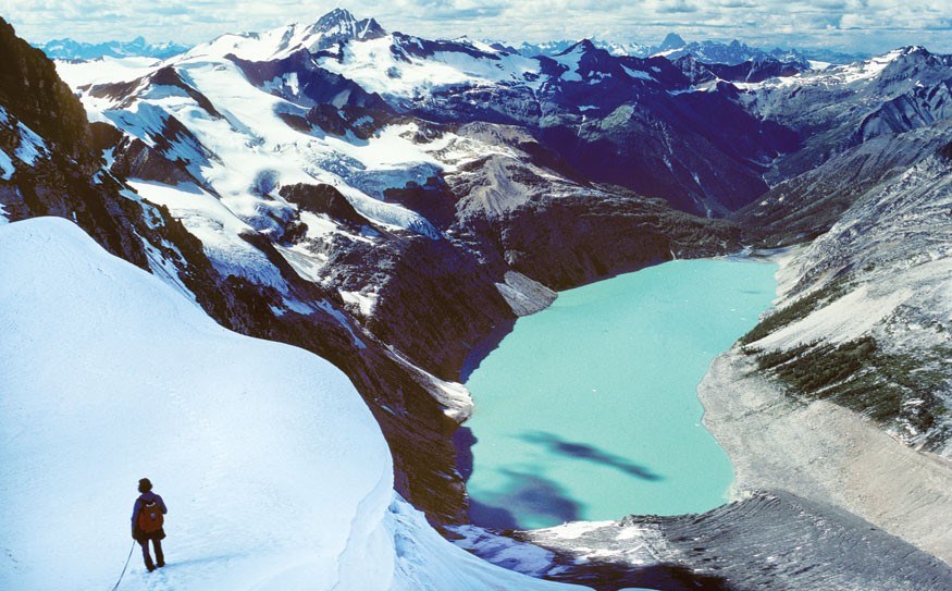 Climber Will Schmidt takes in the view high above Lake of the Hanging Glacier during a 1976 traverse. Glacier Dome (upper left) is planned as a site for a gondola station. Photo by Pat Morrow