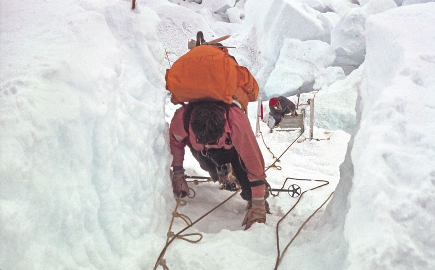 An expedition member climbs up a ladder in the Khumbu Icefall. Photo by Henry S. Hall