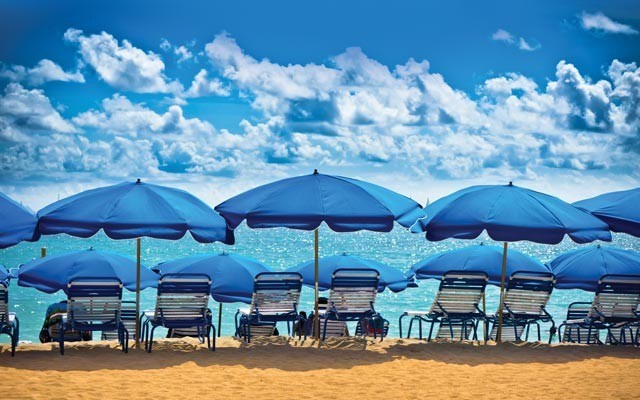 Matching blue umbrellas line the beach front. Photo from shutterstock.com
