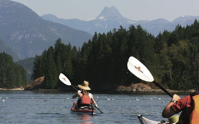 Happy paddlers Two kayakers paddle towards the Stetson-shaped mountain, Mount Doogie Dowler, named after the first postmaster at Campbell River. The mountain is on the mainland, but seems part of the ocean archipelago. Photo by Cathryn Atkinson