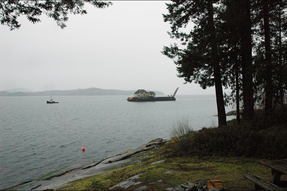 GETTING POSITIONED: Maneuvering in the Salish Sea, towed by tug on a huge barge, is a recycled house from Oak Bay that is being settled near Saltery Bay. The new homeowner said the house has great character, and she was able to purchase it at a fraction of the price it would cost to build a new home.