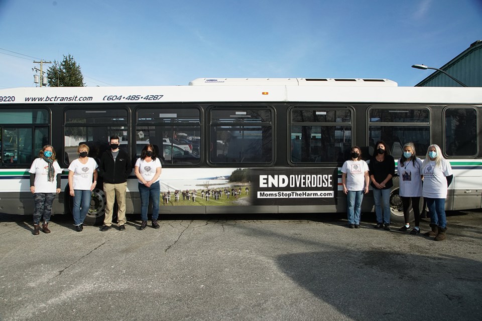 SOMBRE REMINDER: Members of Moms Stop the Harm [from left] Margo Peterson, Lyn Nicol, Rob Fitzpatrick, Darlana Treloar, Maureen Christensen, Marci Hayes, Maggy Gisle and Shirley Gentner gathered by a City of Powell River transit bus fitted with a sign that carries an important message recognizing those who have been affected by substance use overdose and the opioid crisis. Powell River’s Community Action Team paid for placement of the sign, which is designed to create awareness about overdose and substance use.                               