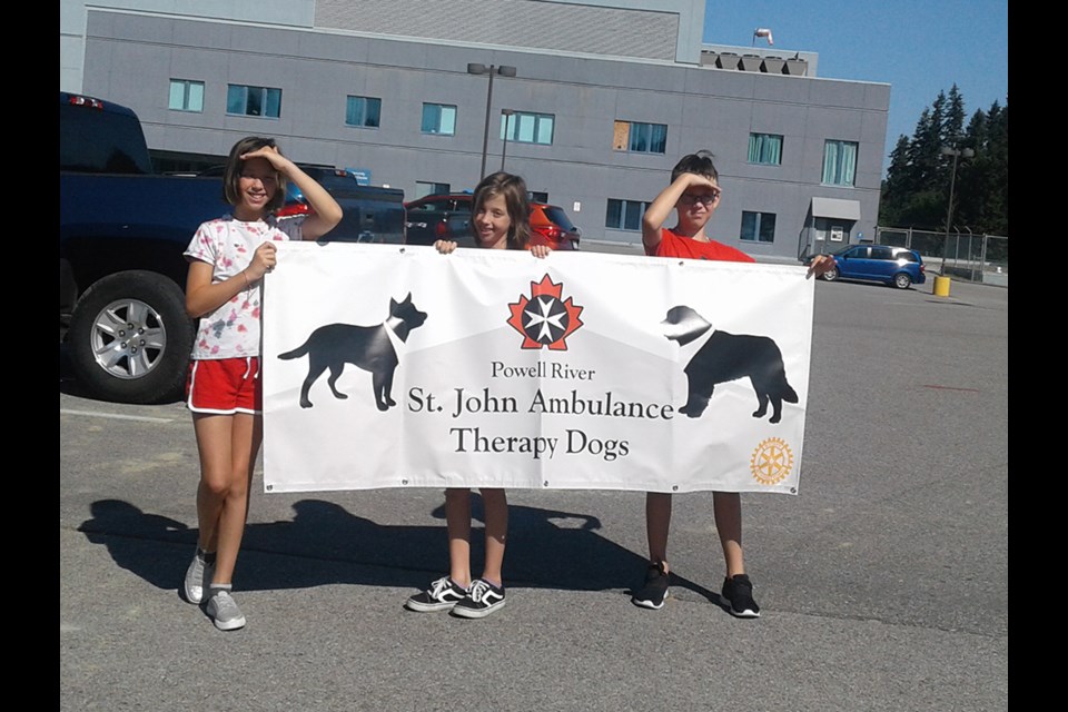 Hailey Baycroft, Abby Baycroft and Korben Baycroft helped by carrying the new St. John Ambulance Therapy Dogs parade banner during an event held on Sunday, July 4, where handlers and dogs visited Powell River health-care facilities.