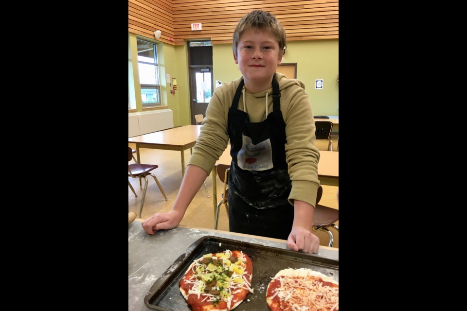 STUDENTS COOK: Westview Elementary School grade 7 student Lukas Parkin uses garden ingredients on a pizza he made while attending the Kids in the Kitchen program.

