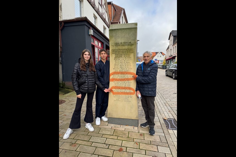 IMPORTANT MEMORIAL: Retired psychiatrist Dr. Peter Uhlmann took a trip to Bad Driburg, the hometown in Germany of his parents and family for generations, with grandchildren Wrenwin Angell [left] and Banks Burr. The family is pictured standing by a memorial in the city on the main street for Jewish people of the town who were killed by the Nazis. Uhlmann has been going to local schools to speak about how the holocaust affected his family.