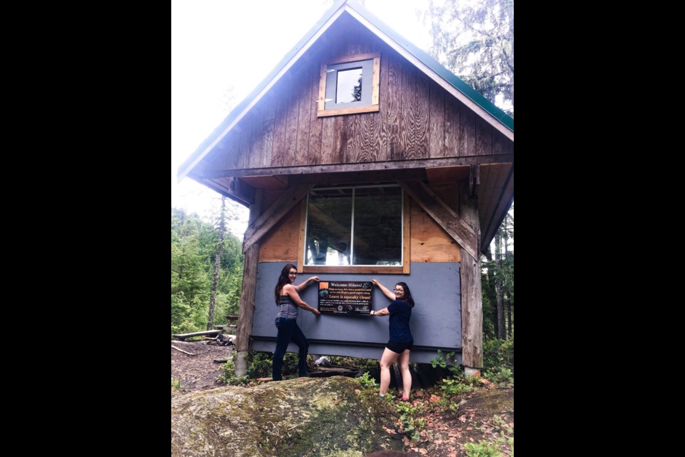 HIKER HUTS: Tourism Powell River assistant manager Emily Fahey [left] and field supervisor Melanie Anaka hold up a new sign posted at the SCT huts.
