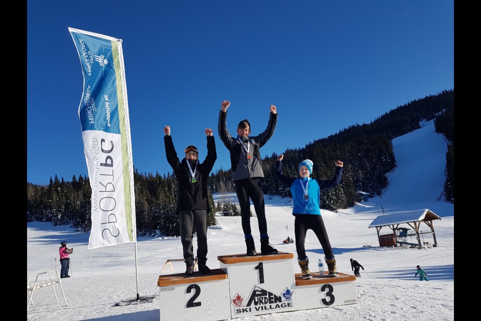 Isaac Hausot (middle) raises his hands in celebration after winning gold for the Prince George Alpine Ski Club at the 2019 TECK North Zone regionals at Purden Ski Hill (via Handout photo)