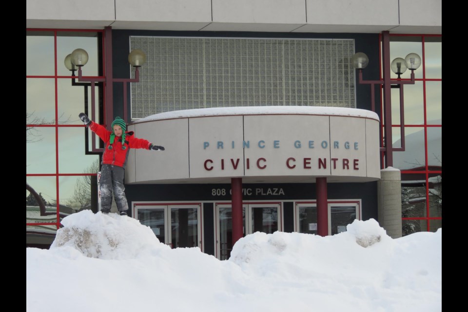 A kid stands on top of a snowbank outside the Prince George Conference and Civic Centre (via Facebook/Prince George Civic Centre)