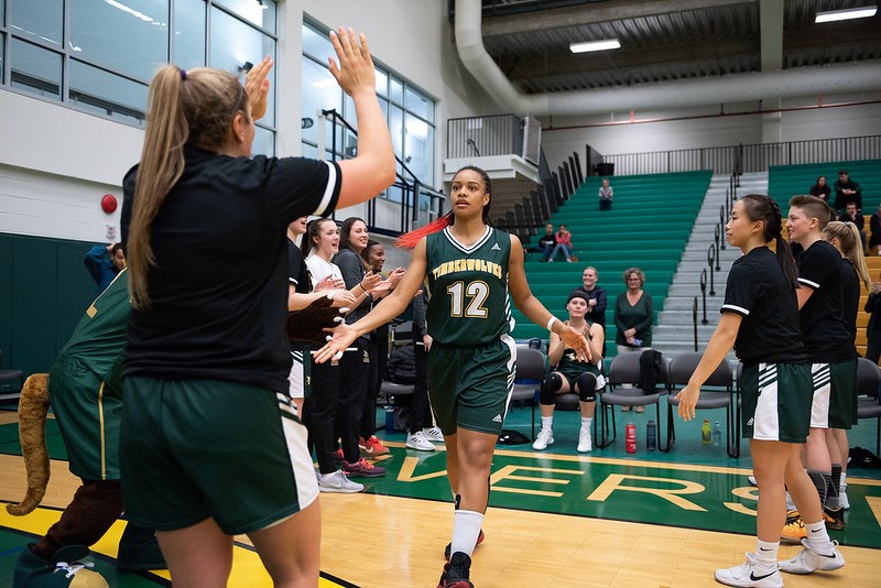 Maria Mongomo (#12) high fives her teammates at the start of a UNBC Timberwolves' basketball game (via UNBC Athletics)