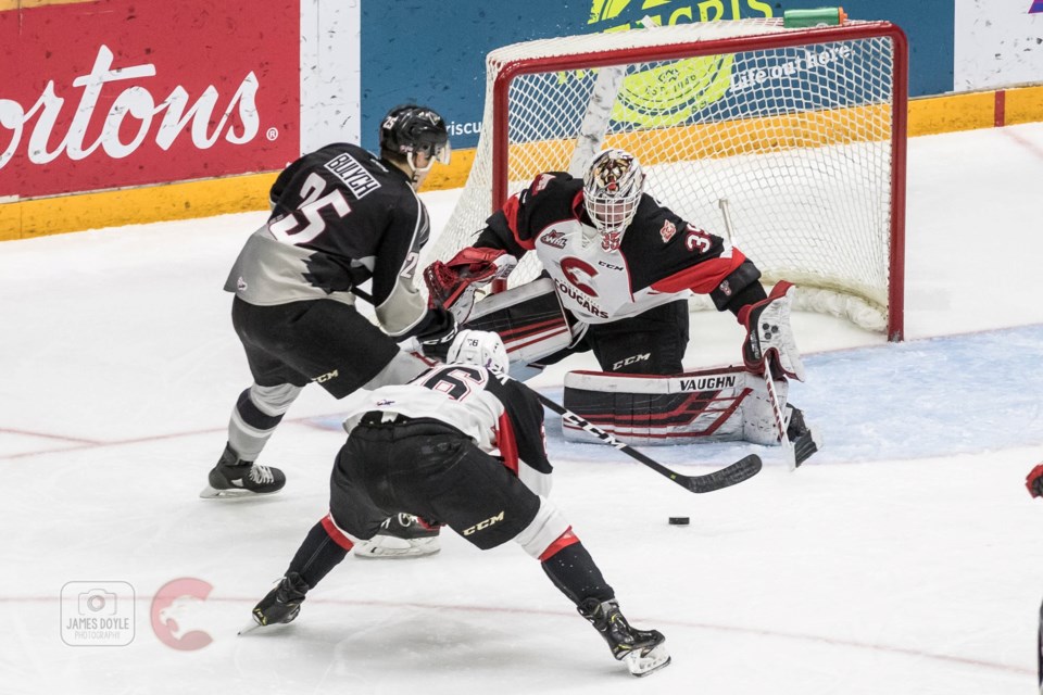 Taylor Gauthier (#35) defends his net as a Vancouver Giant skates on the attack with Ryan Schoettler (#16) chasing behind him (via Prince George Cougars/James Doyle Photography)