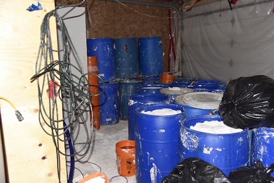 Blue barrels and black garbage bags containing waste by-products. (via RCMP)