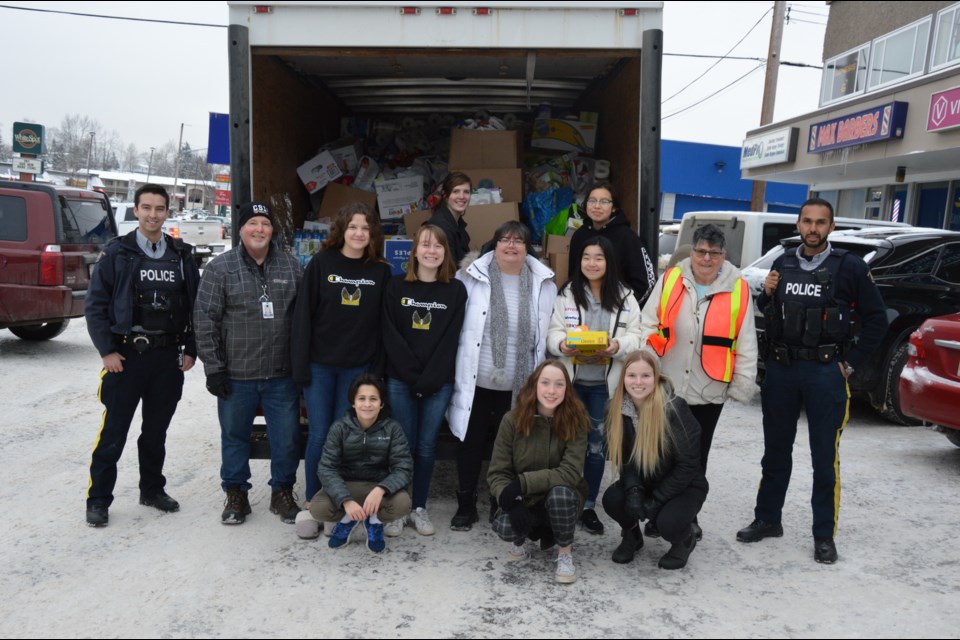 Police officers, detachment staff and volunteers empty a cube van of donated food to the Council of Seniors.  (via Prince George RCMP)