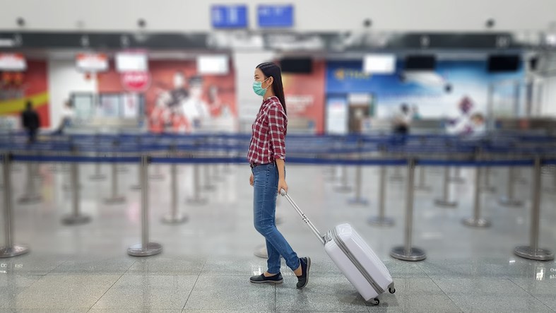 A masked-up air traveller walks through an empty airport.