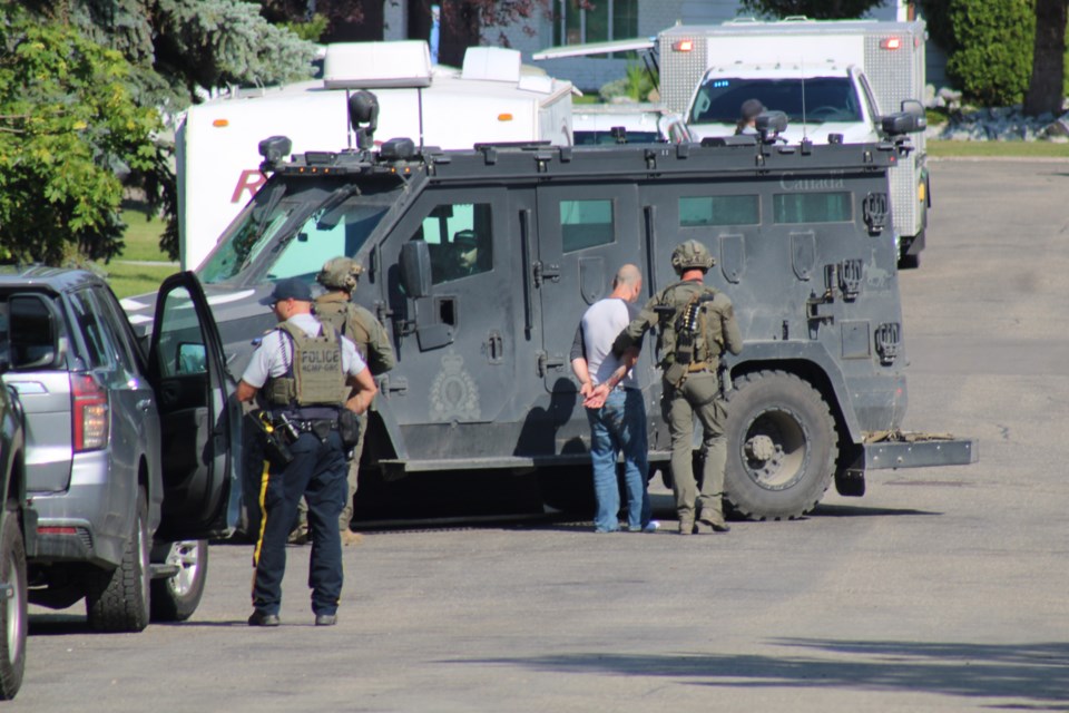 Police lead a man in handcuffs towards an armoured vehicle on Oliver Avenue in Prince George on the afternoon of Friday, Aug. 1, 2025.