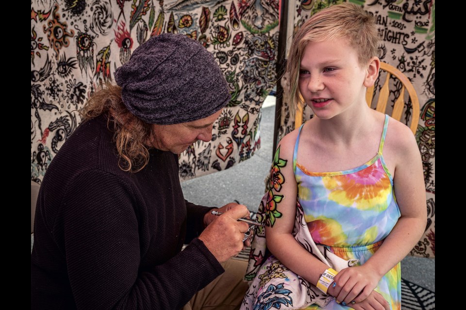Emily Hall celebrates her ninth birthday by getting a spray on tattoo by artist Chris Crash of Penticton, who has been doing airbrush art for 38 years, while attending the BCNE Sunday, August 17, 2025.