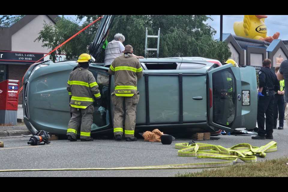Prince George Fire Rescue and BC paramedics help a woman climb out after a vehicle rollover on Central Street East on Friday, Aug. 15, 2025 in Prince George, BC.