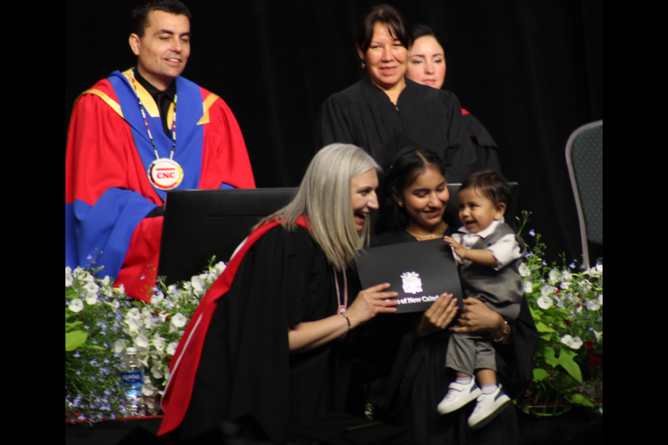 CNC president Cindy Heitman presents a certificate to a grad and her child on Thursday, June 5, 2025 In Prince George, BC.