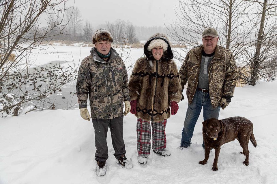 Paul Cailleaux (left), Margaret and Gord Smith and Reese the labrador retriever all have a hand in feeding ducks that didn't fly south for winter at Cottonwood Island Park.
