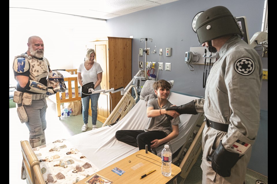 Nicholas Gallagher, 12, appears a bit shocked as he shakes the hand of Brian Stewart, dressed as an All-Terrain Scout Transport Driver, while mom Brenda and Jason Medcraft, dressed as Captain Rex, watch.  Members of the Star Wars 501st Legion visited the pediatrics department at UHNBC Friday morning to introduce some of the staff and patients to characters from the movie franchise.

