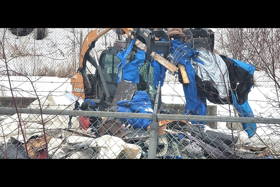 A bobcat operator picks up a load of tarps used at one of the abandoned shelter sites at Moccasin Flats on Wednesday, Jan. 14 , 2025.