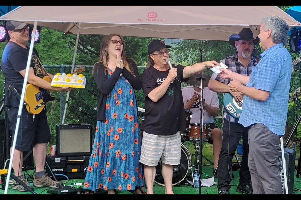 Prince George liquor/cannabis retailer Cameron Thun hired the Rick Stavely Band for his wife Tammy's backyard birthday party on June 22. In the photo, Tammy watches while Cameron hands over a $5,000 cheque to Darrell Roze, executive director of the Child Development Centre of Prince George and District.
